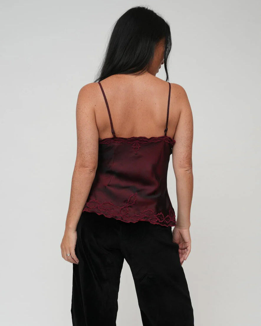 Back view of a Woman wearing a burgundy lace camisole against a plain background, bohemian silk cami