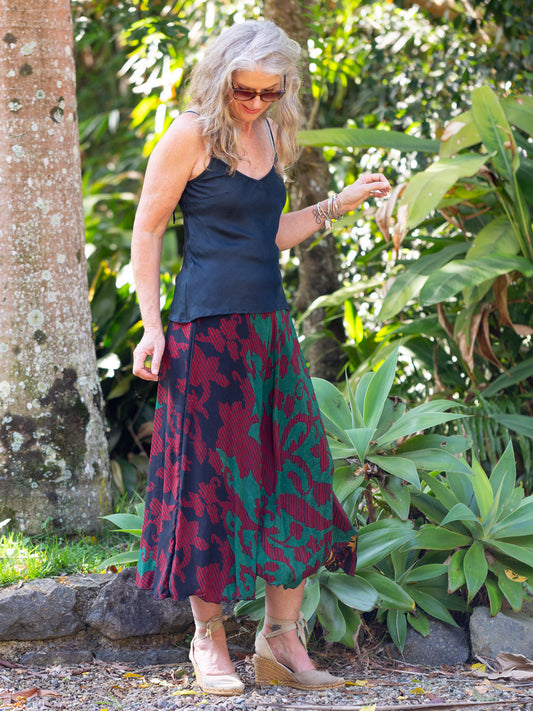 Woman in a garden wearing a navy top and patterned skirt.