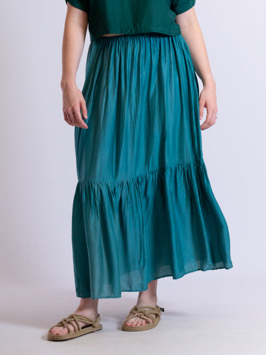 Woman wearing a teal skirt with a plain background