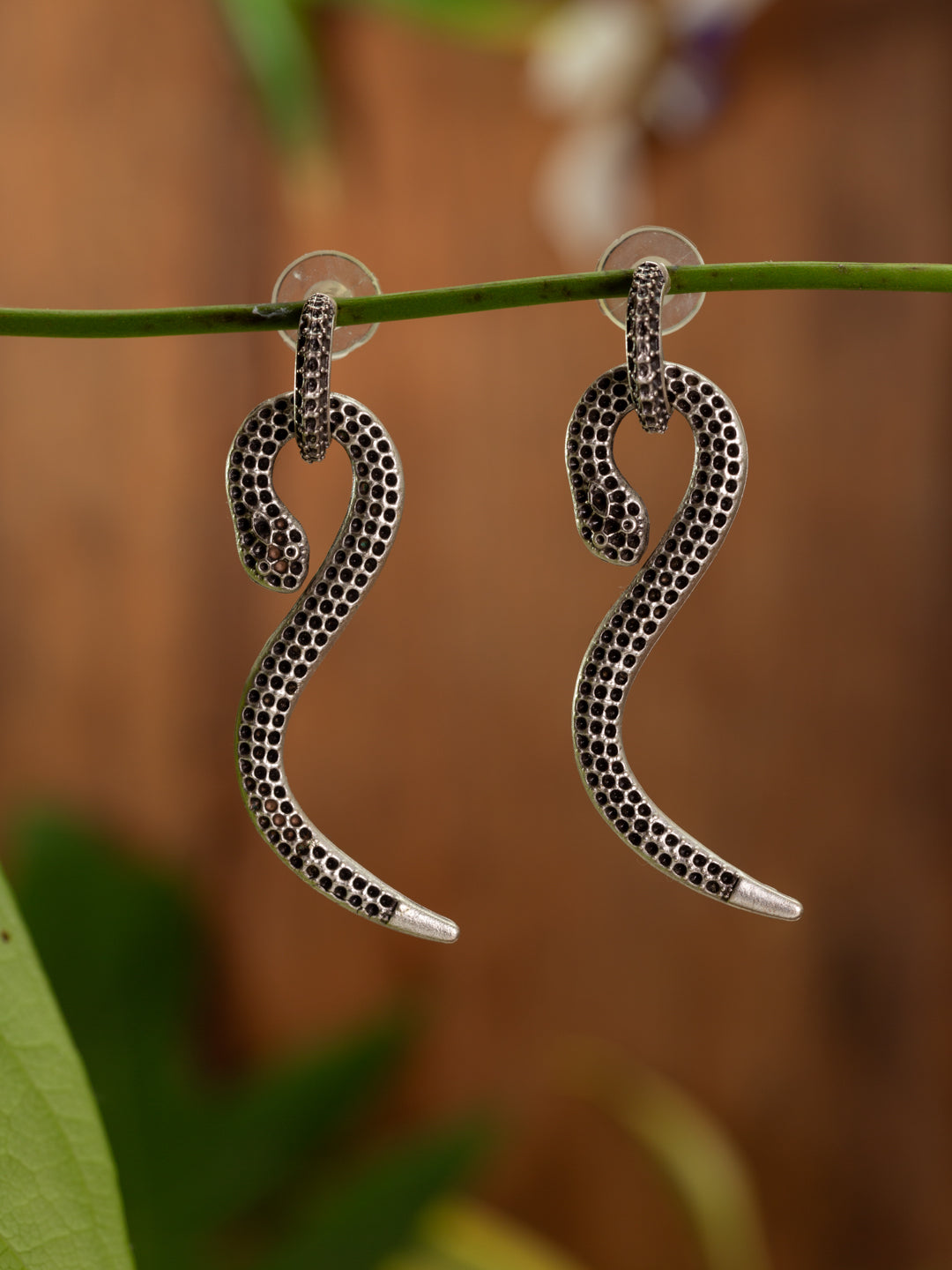 Snake like earrings on a silver hoop, backdrop of timber