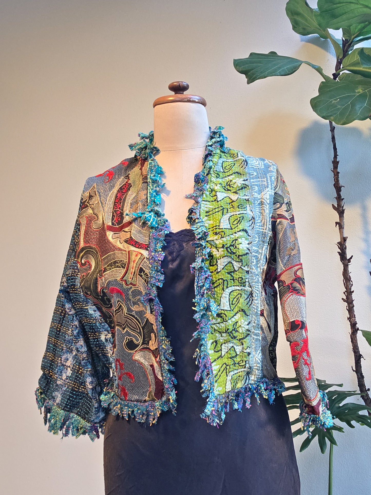 Colorful embroidered jacket on a mannequin with a plant in the background