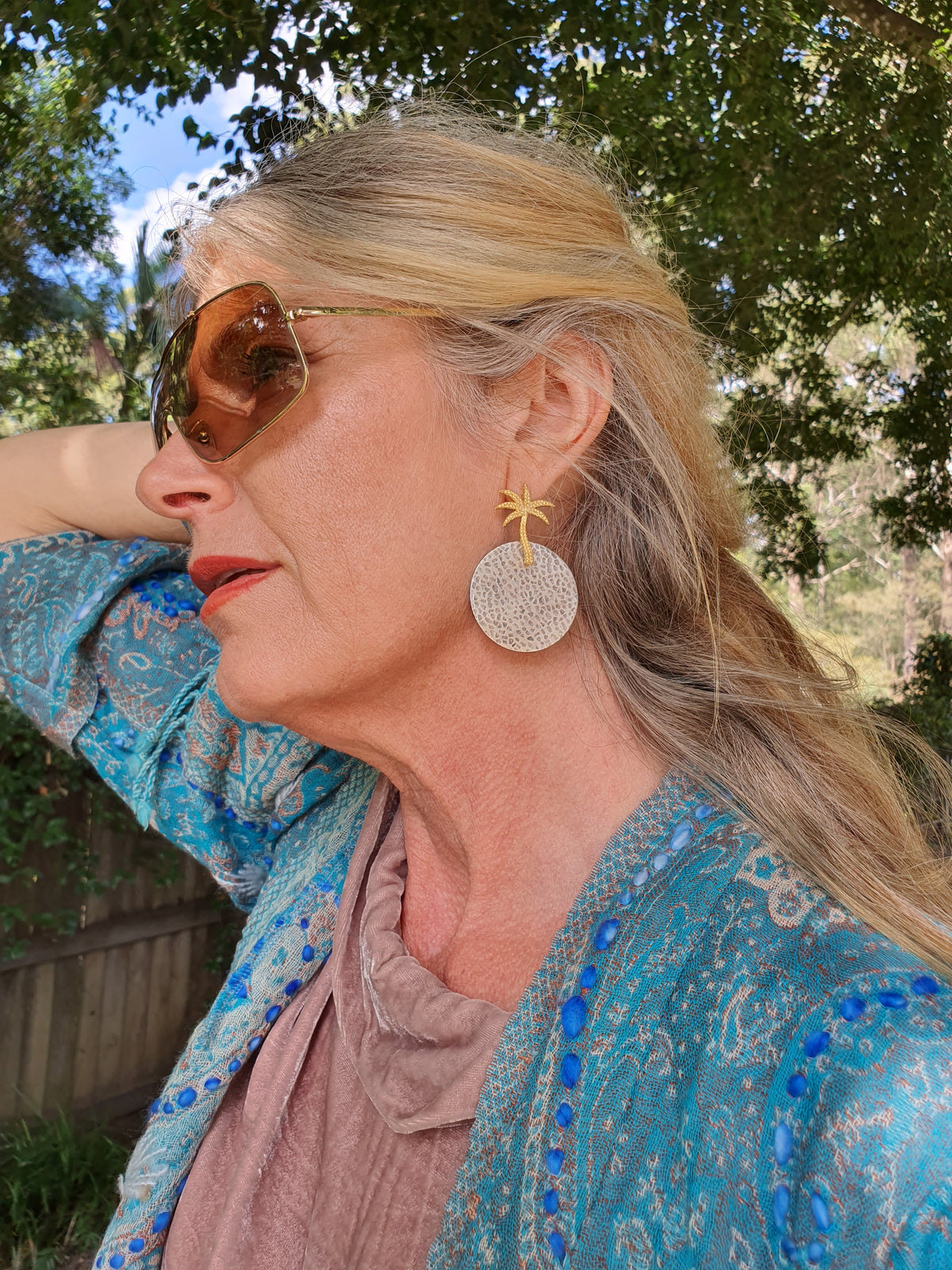 Lady wearing silver and gold palm tree earrings