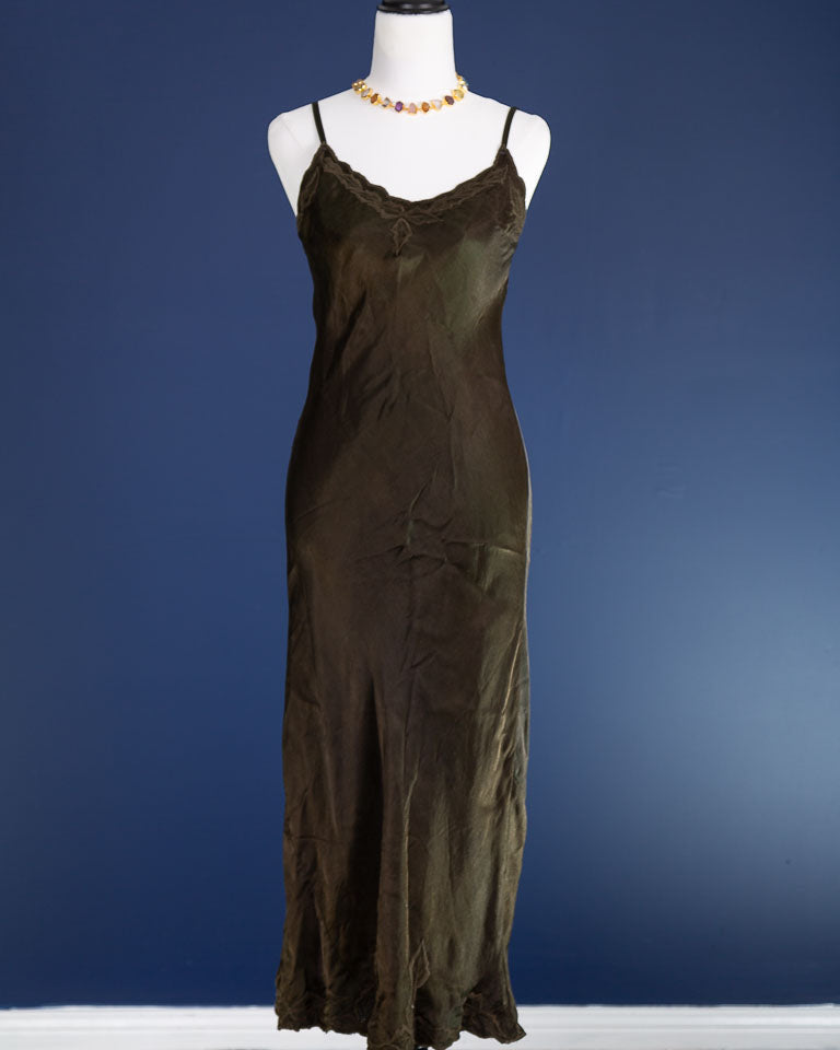 Dark olive slip dress on a mannequin against a blue background