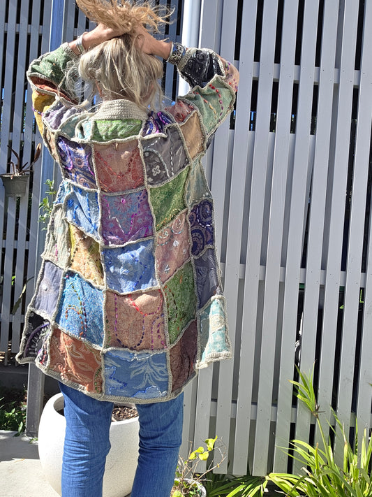 Person wearing a colorful patchwork coat on a bench