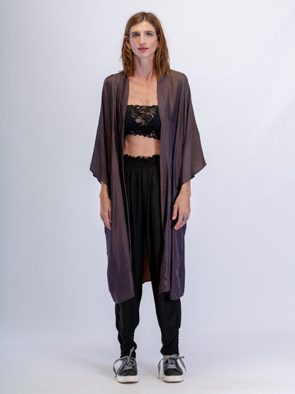 Woman wearing a long dark bronze kimono over a black outfit on a white background