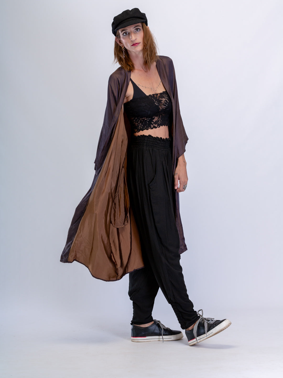 Woman wearing a long brown kimono over a black outfit with a white background