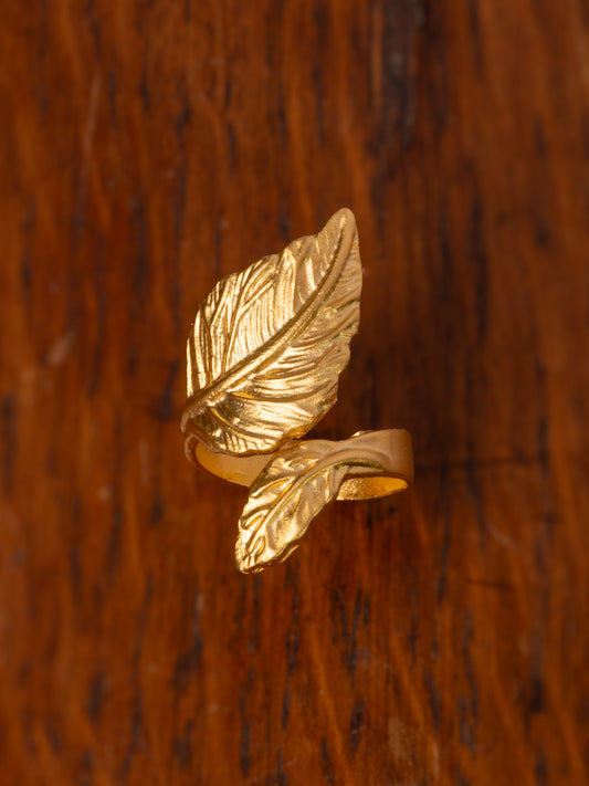 Gold leaf-shaped ring on a wooden surface