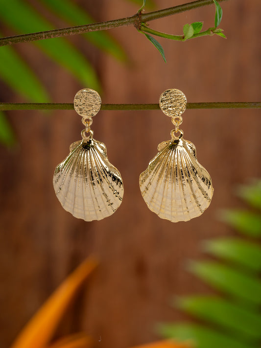 Gold shell-shaped earrings on a branch with a blurred natural background