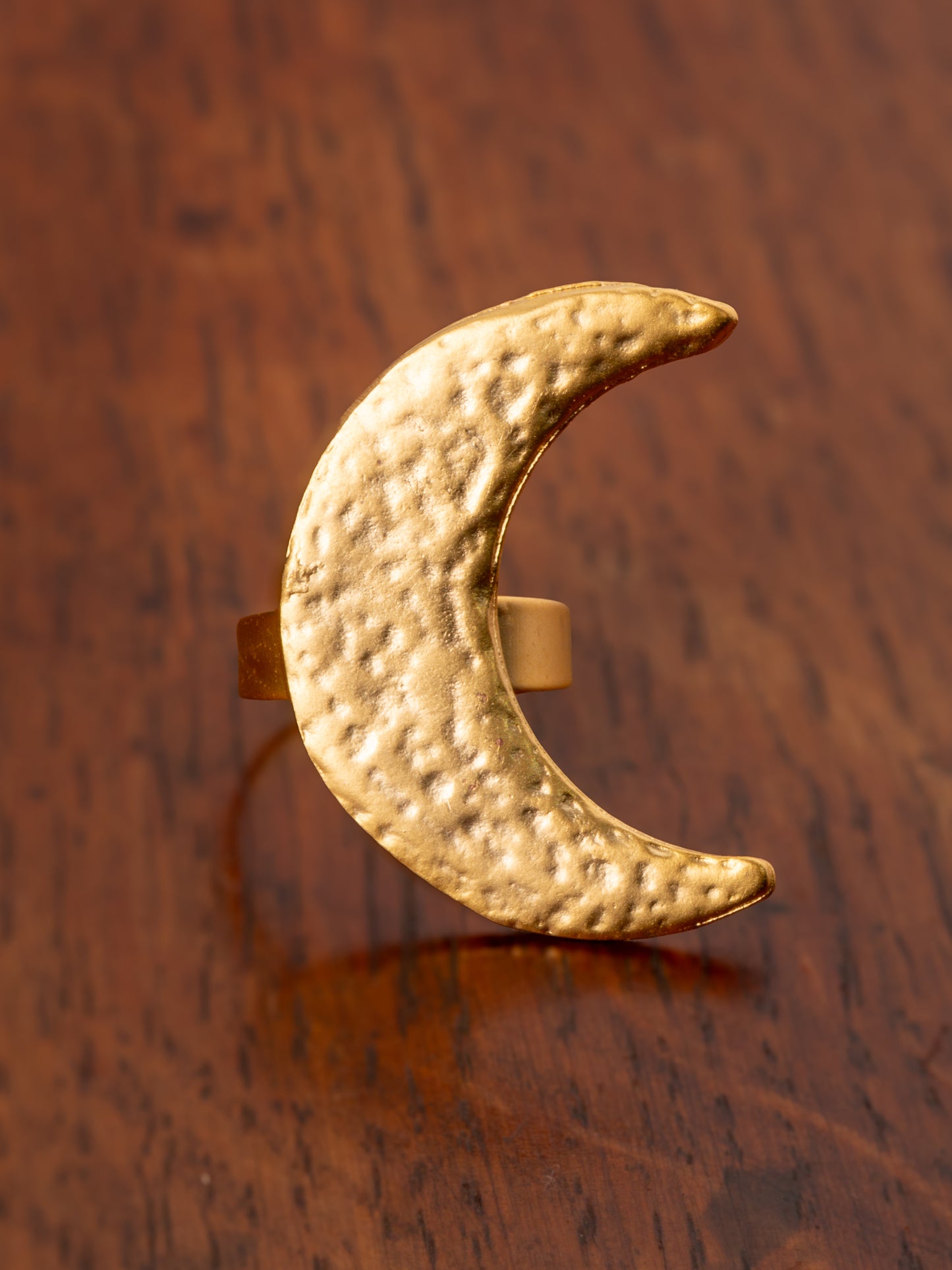 Gold crescent moon ring on a wooden surface