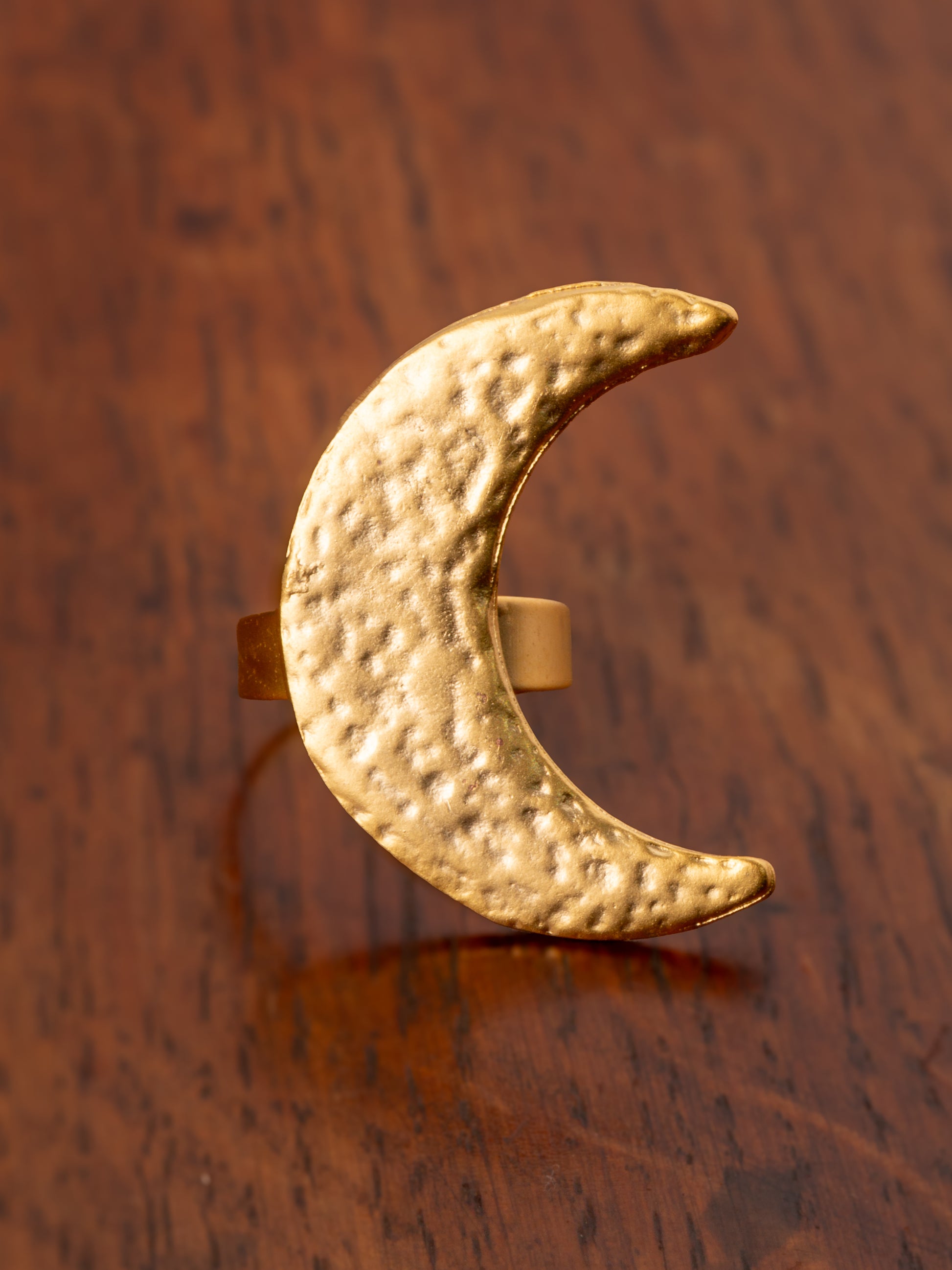 Gold crescent moon ring on a wooden surface