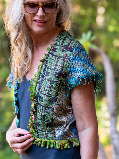 Woman wearing a colorful patterned top with a blurred natural background