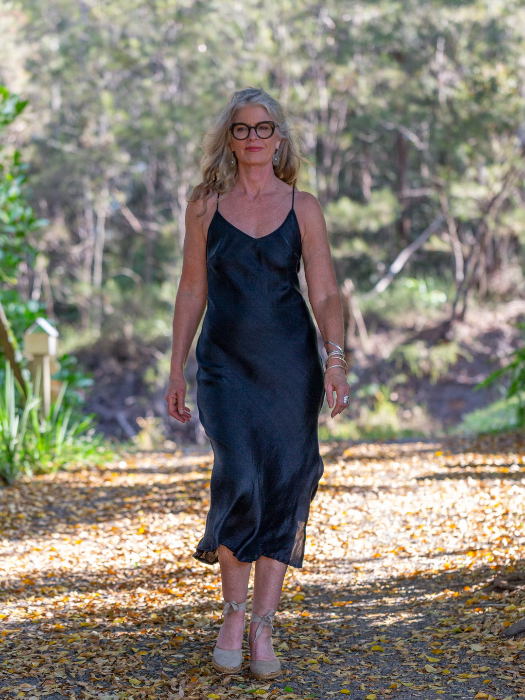 Woman in a black dress standing outdoors with trees in the background
