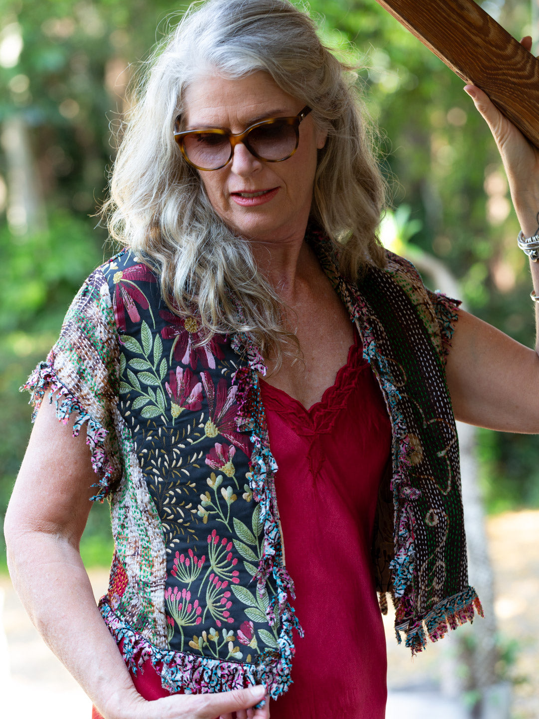 Woman wearing a colorful floral vest over a red top outdoors
