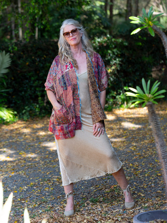Woman wearing a patterned kimono over a dress in a garden setting