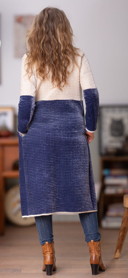 Person wearing a long blue and white velvet coat in an indoor setting