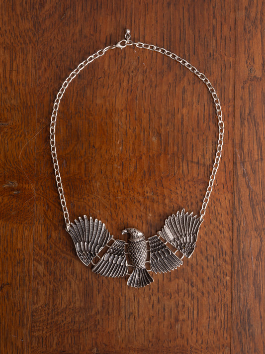 A large eagle in moving parts necklace against a timber surface