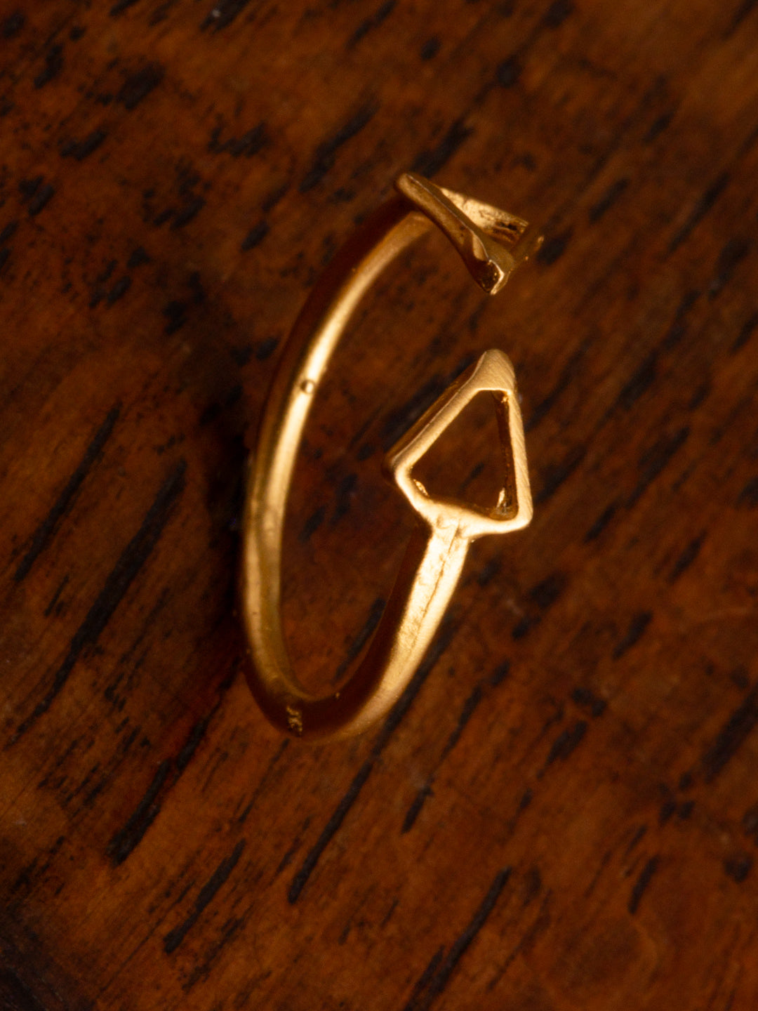 A double arrow gold ring on a timber backdrop