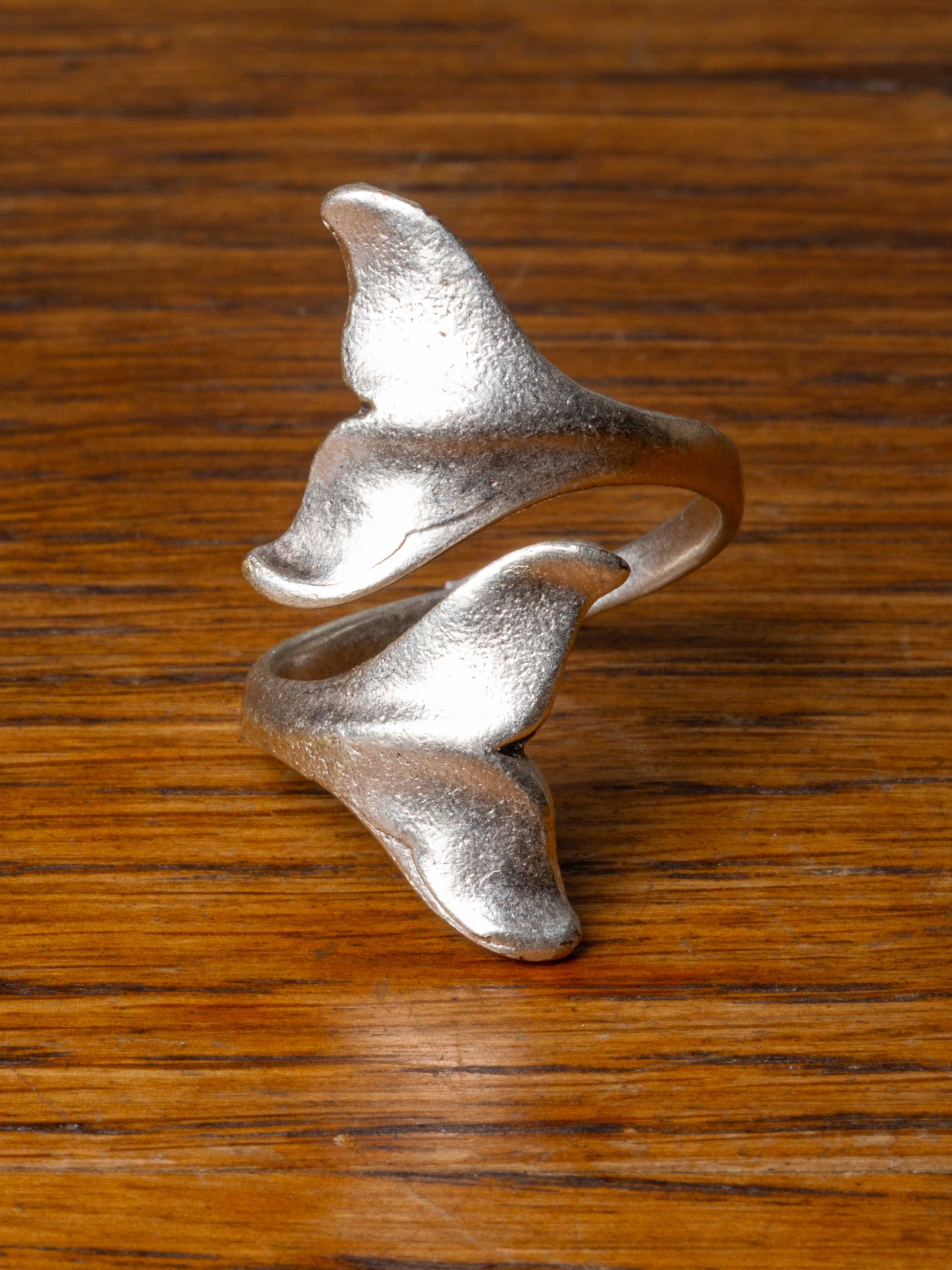 silver ring with two whale tails wrapping around finger