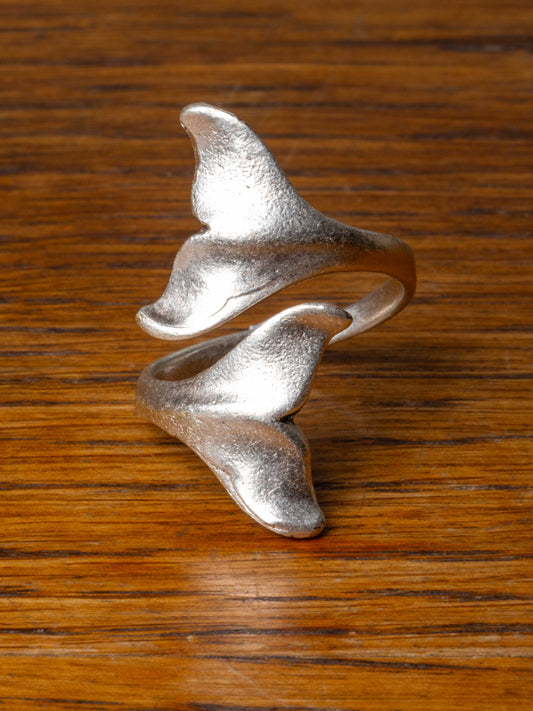 silver ring with two whale tails wrapping around finger