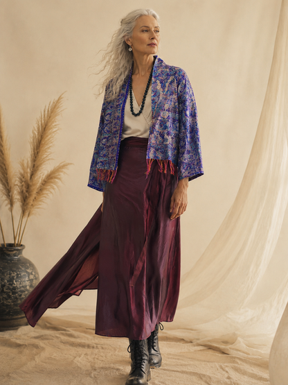 Woman wearing a blue patterned jacket and purple skirt in a studio setting