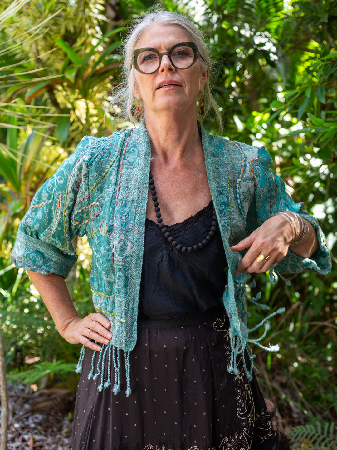 Woman wearing a teal knitted cardigan in a forest setting