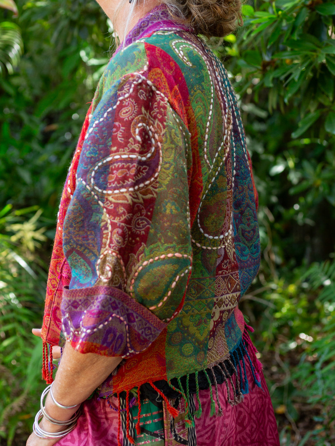 Person wearing a colorful patterned jacket with a green leafy background