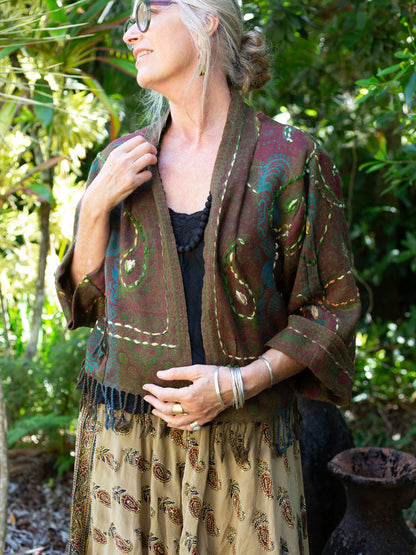 Woman wearing a patterned jacket and dress in a forest setting
