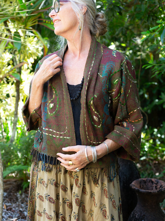 Woman wearing a patterned jacket and dress in a forest setting