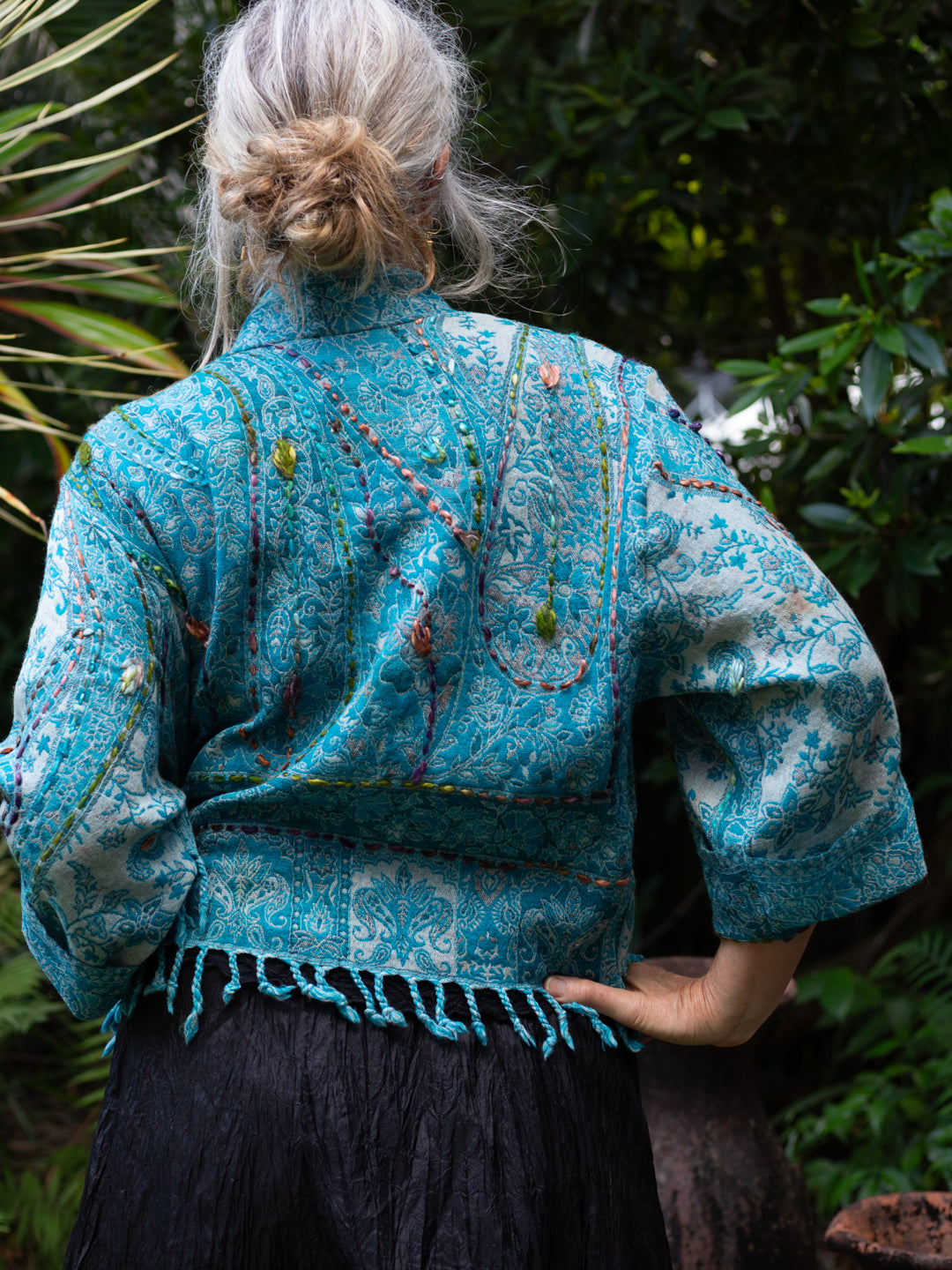 Person wearing a blue embroidered jacket in a natural setting