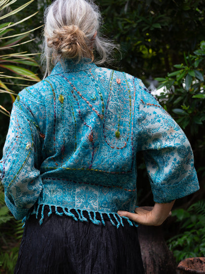 Person wearing a blue embroidered jacket in a natural setting