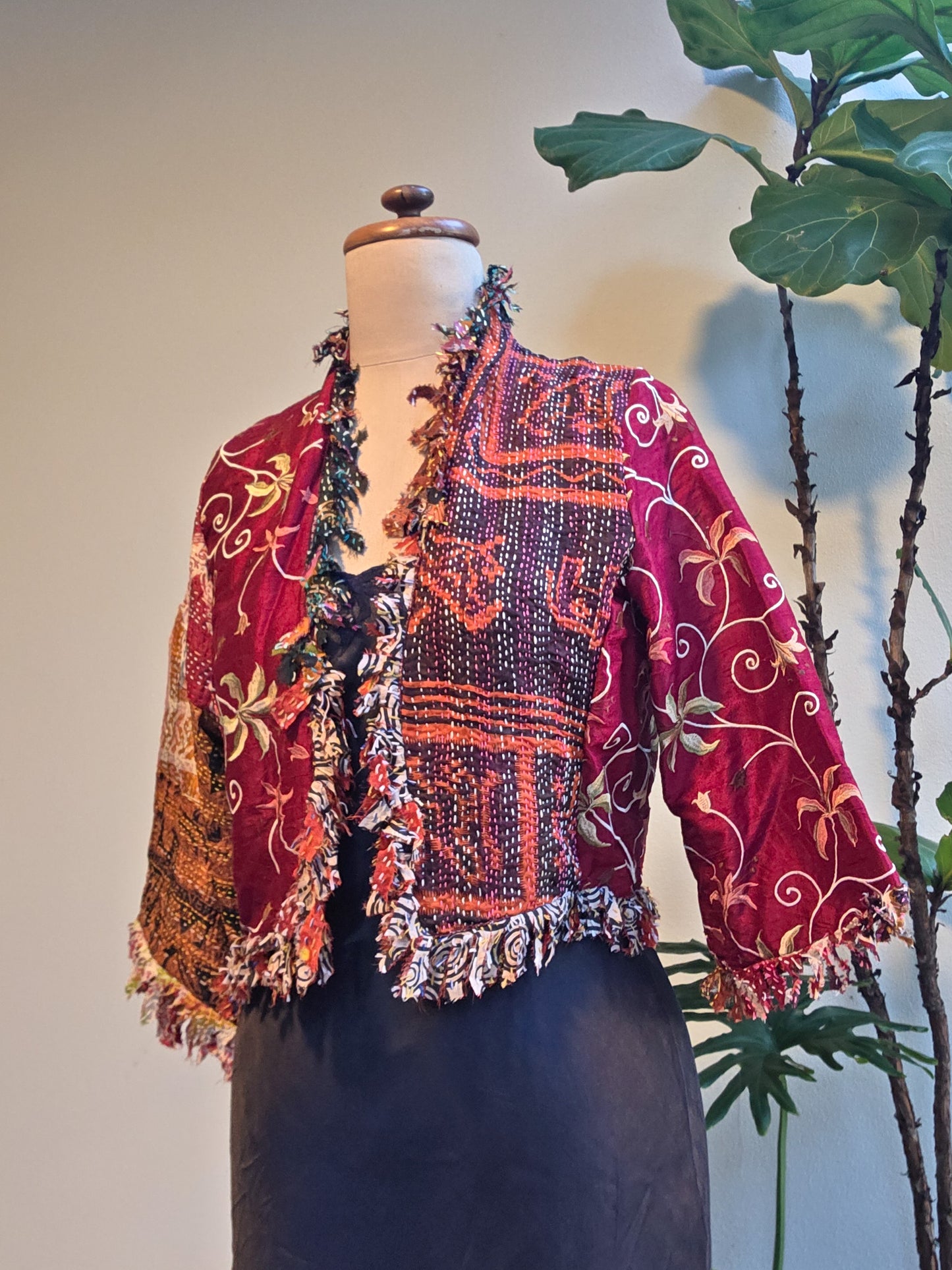 Colorful patterned jacket on a mannequin with a plant in the background