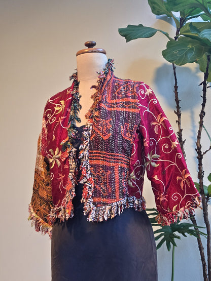 Colorful patterned jacket on a mannequin with a plant in the background