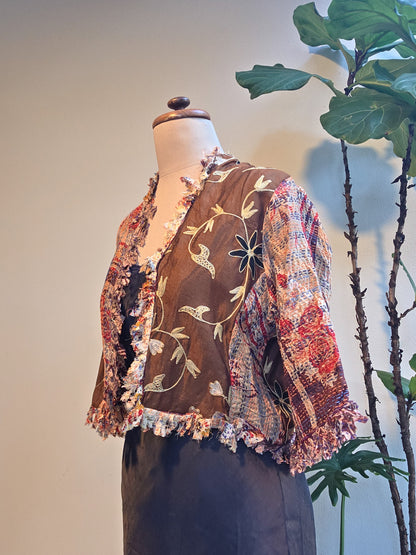 Mannequin wearing a colorful embroidered jacket with a plant in the background, silver cocoonz