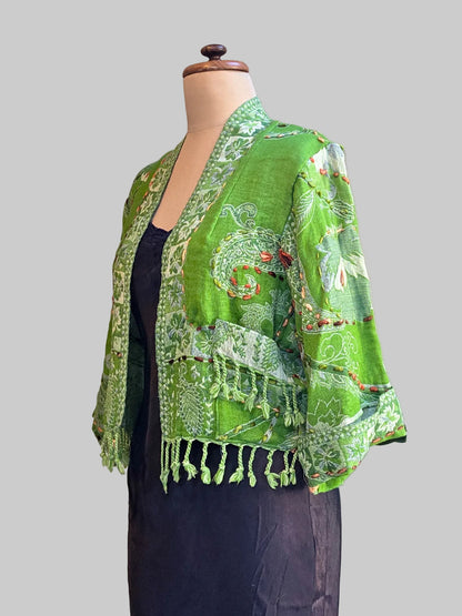 A bright green wool fringed jacket on a black slipped mannequin against a neutral background
