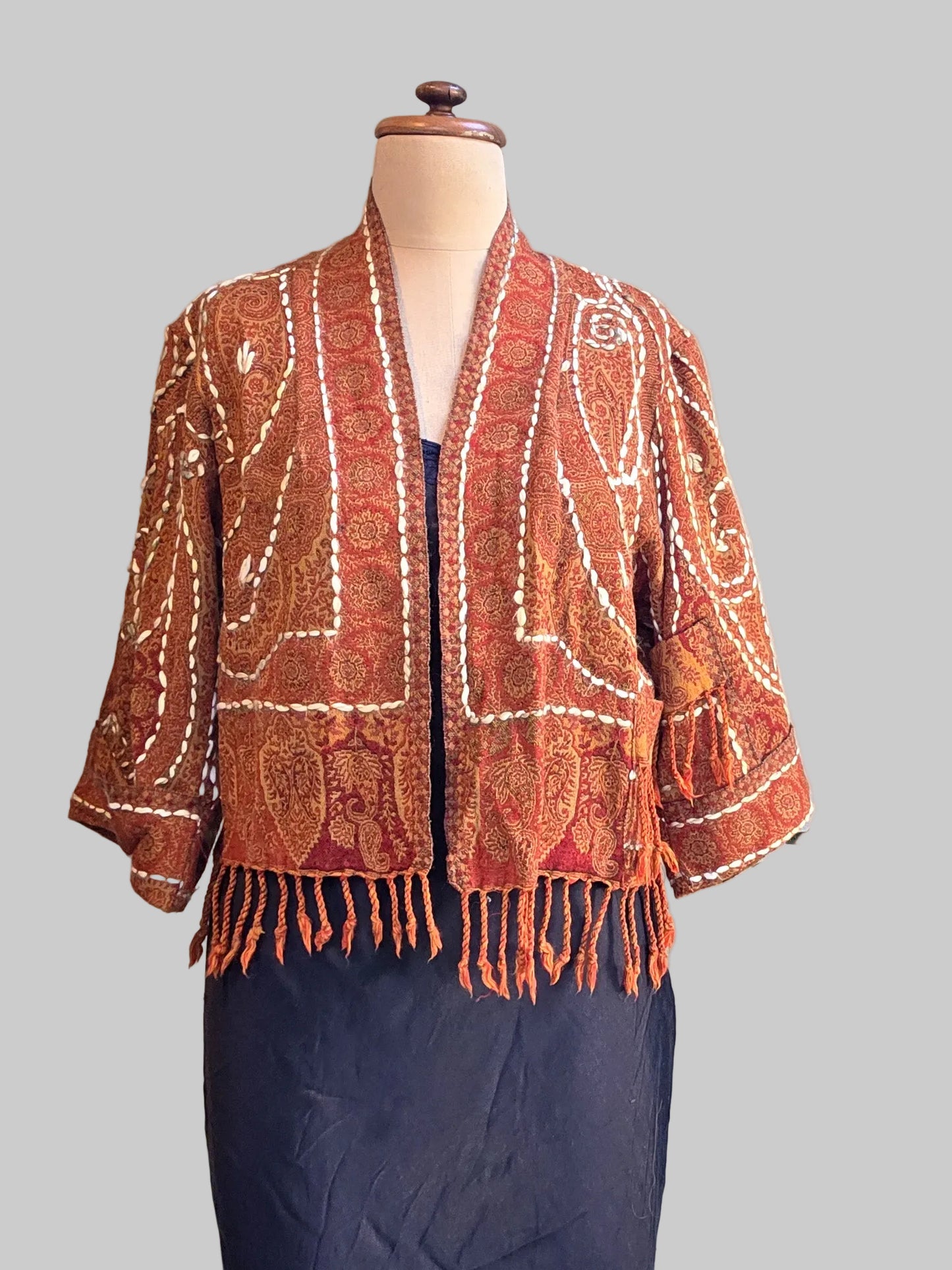 Rust coloured wool fringed jacket on a mannequin with black slip and neutral background