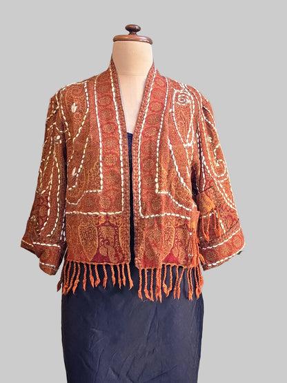 Rust coloured wool fringed jacket on a mannequin with black slip and neutral background