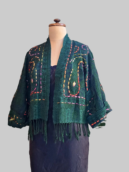 A deep green fringed wool jacket on a black slip dress