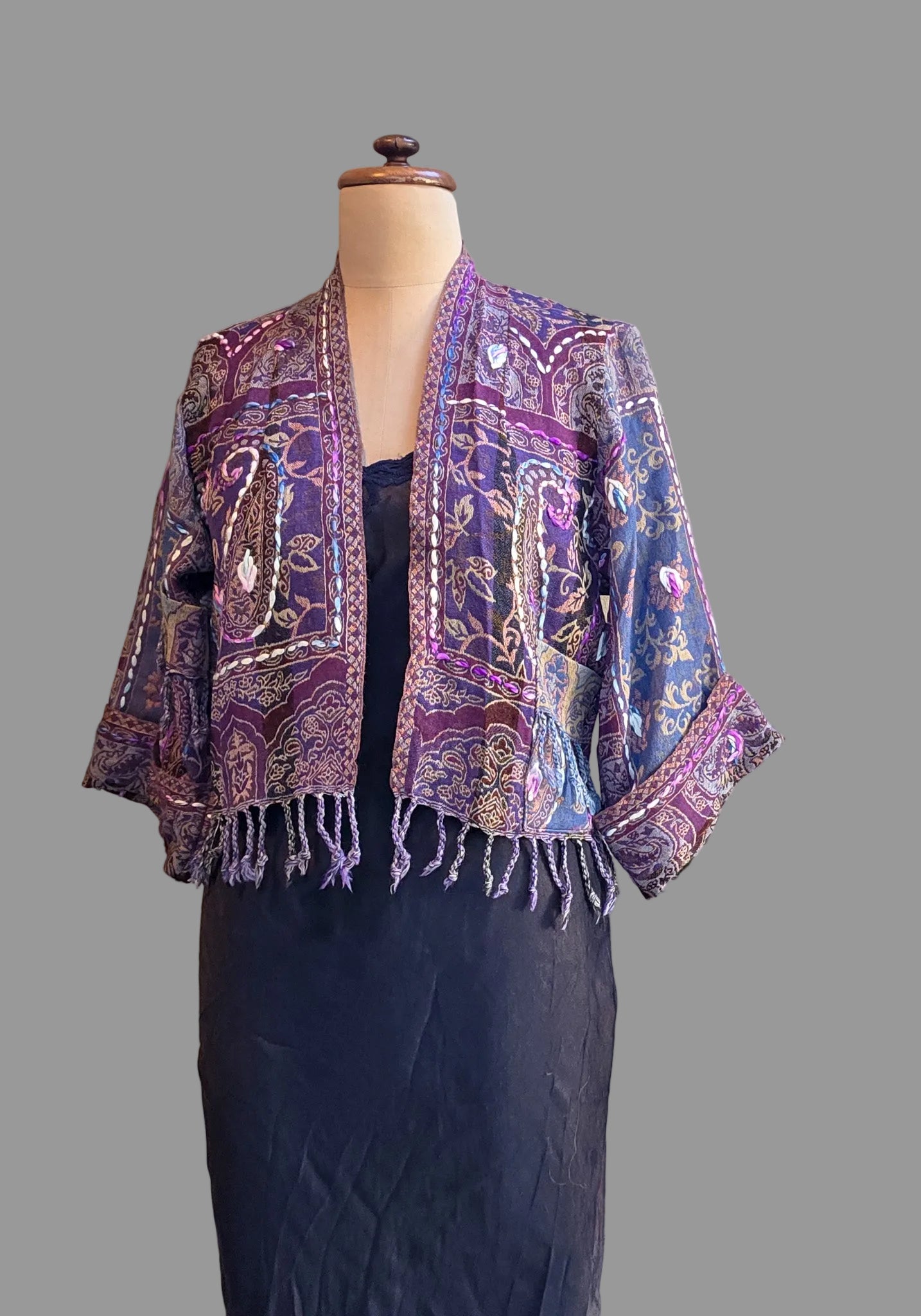 A mauve and lilac wool fringed jacket on a mannequin against a neutral backgound