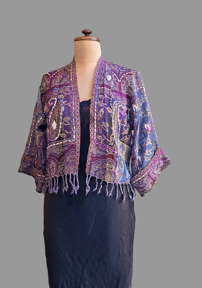 A mauve and lilac wool fringed jacket on a mannequin against a neutral backgound