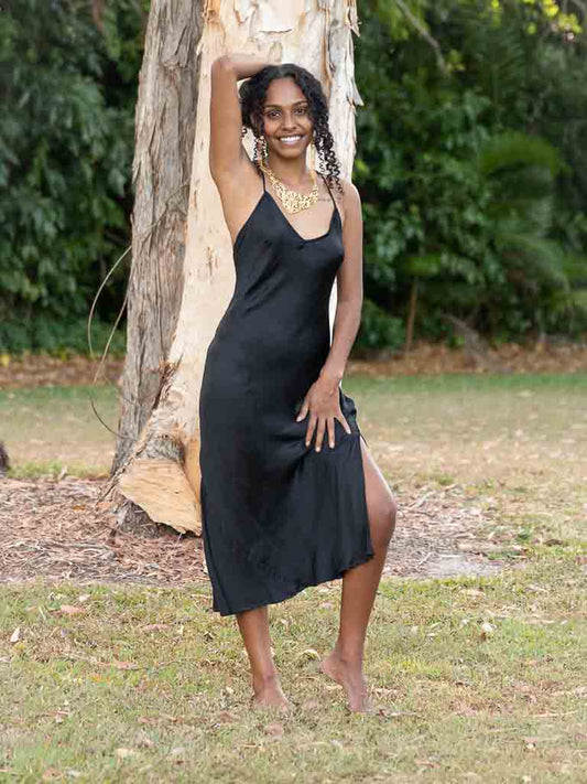 Model wearing a black slip dress with side split