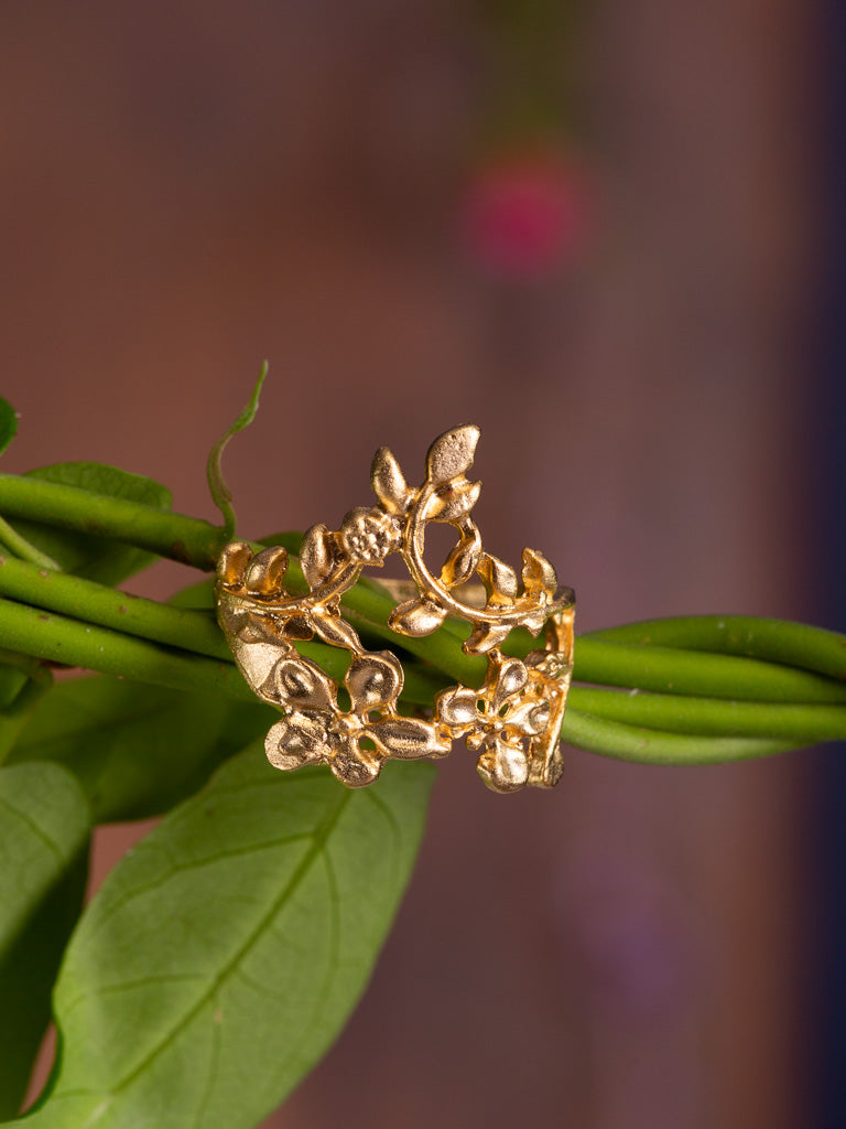 A delicate scroll flower design in an adjustable gold ring