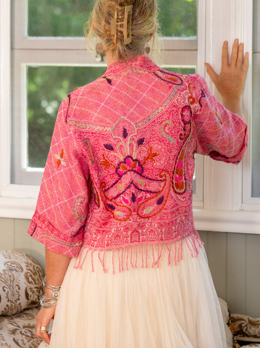 Person wearing a pink embroidered jacket with a white background
