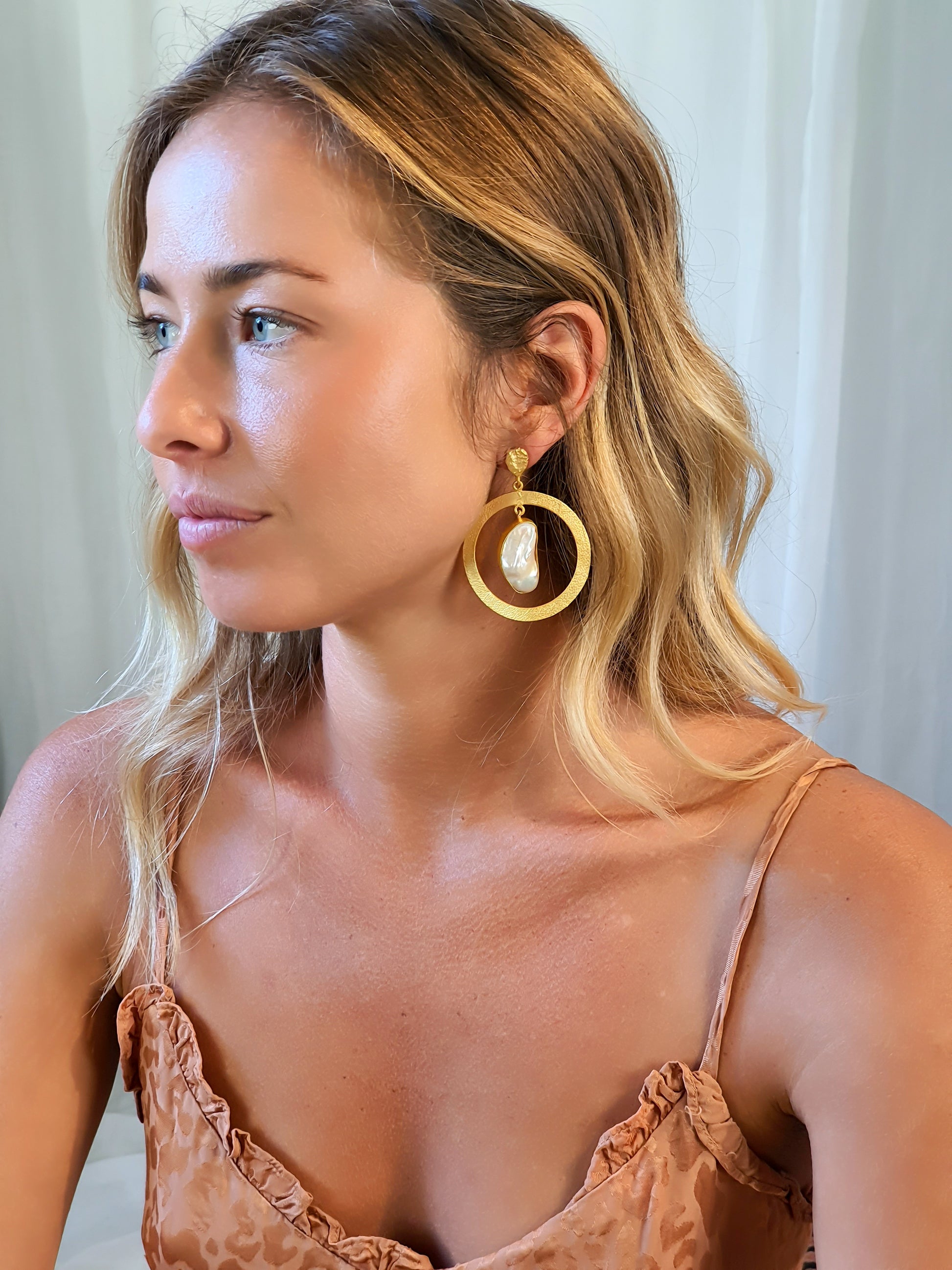 Woman wearing large gold and pearl hoop earrings