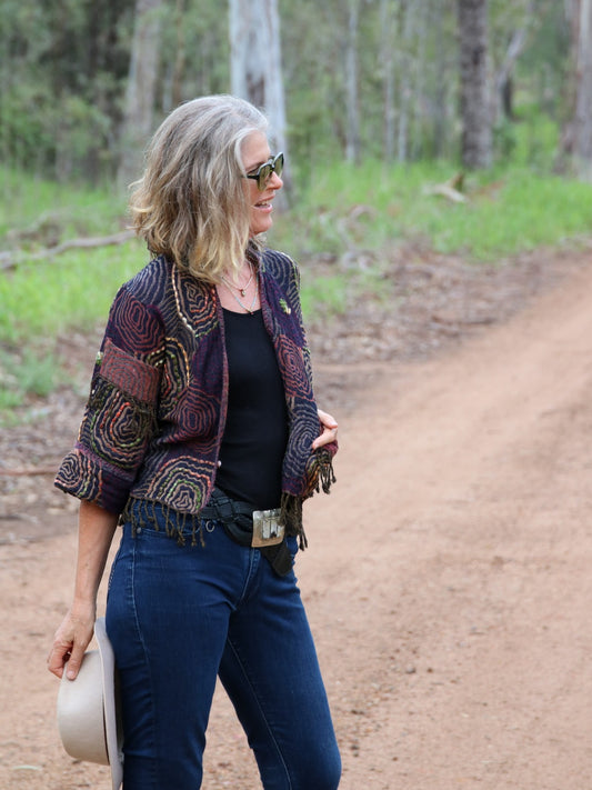 Woman wearing a wool fringed jacket in aubergine tones