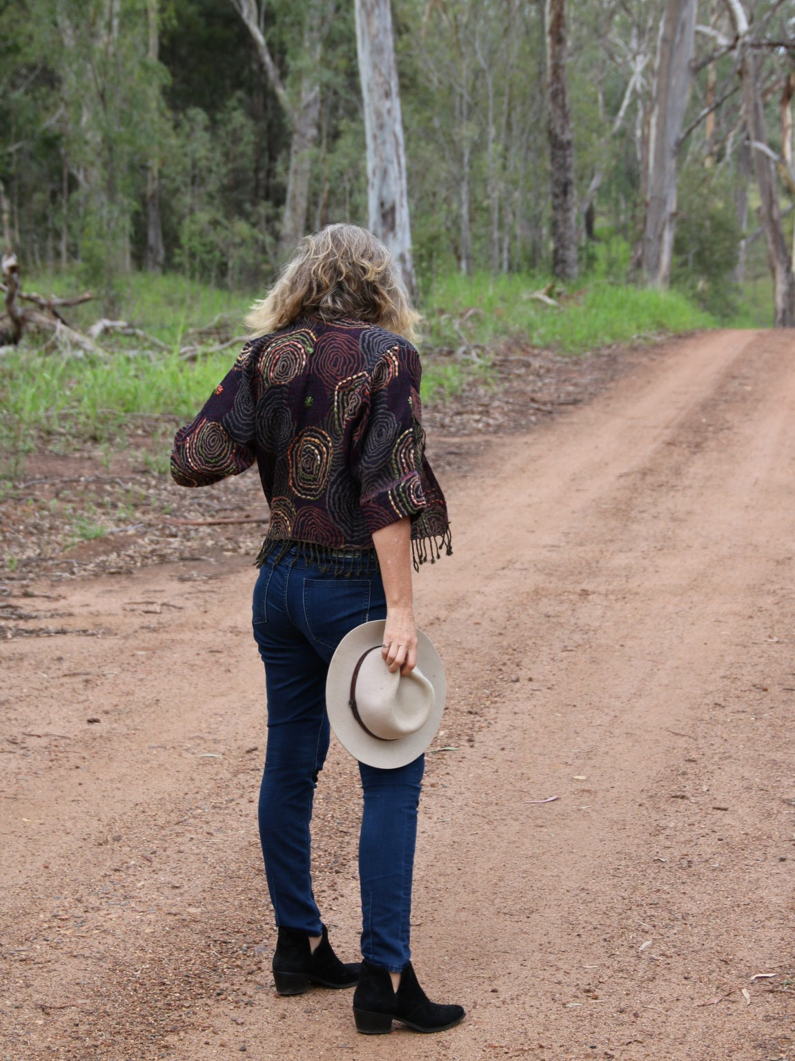 Back view of a lady with wool jacket on dirt road