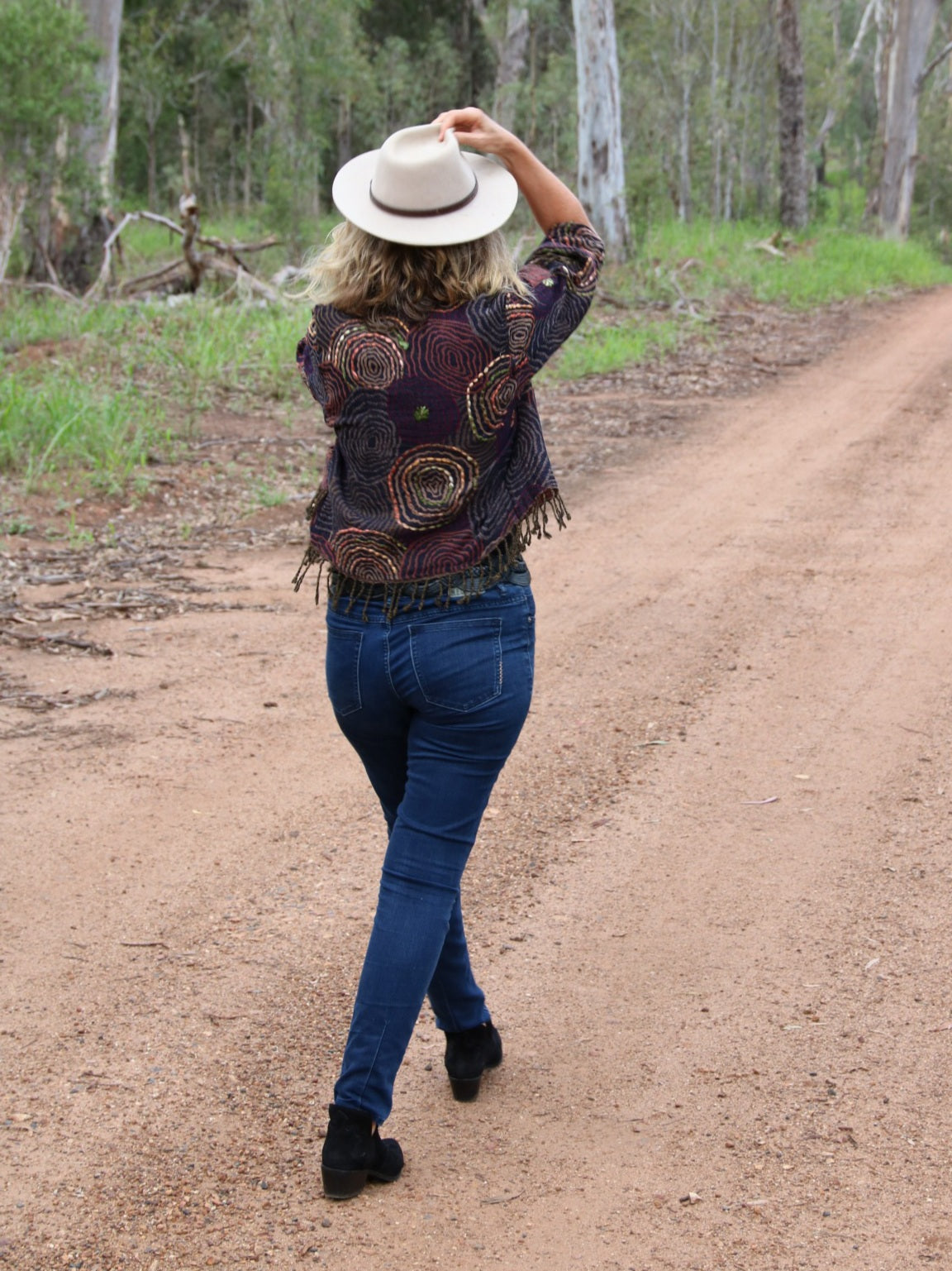 Woman wearing a fringed jacket with boots and hat