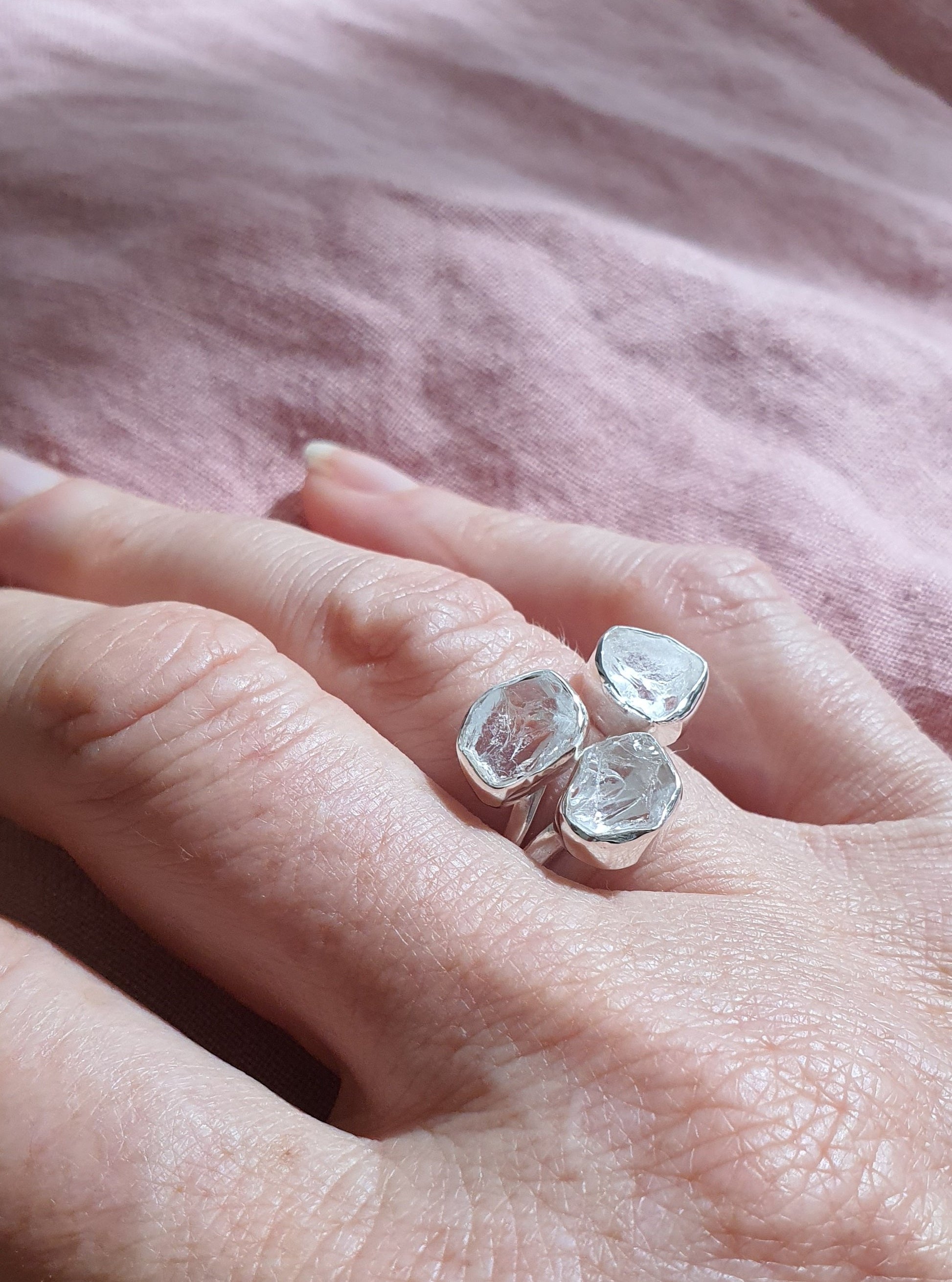 A silver ring with three clear quartz raw cut crystals