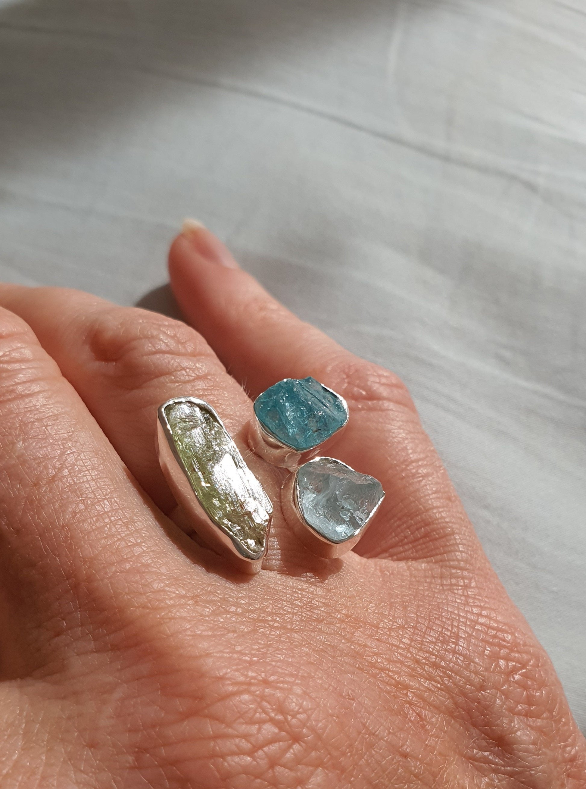 A silver ring with raw cut crystals in blues and greens