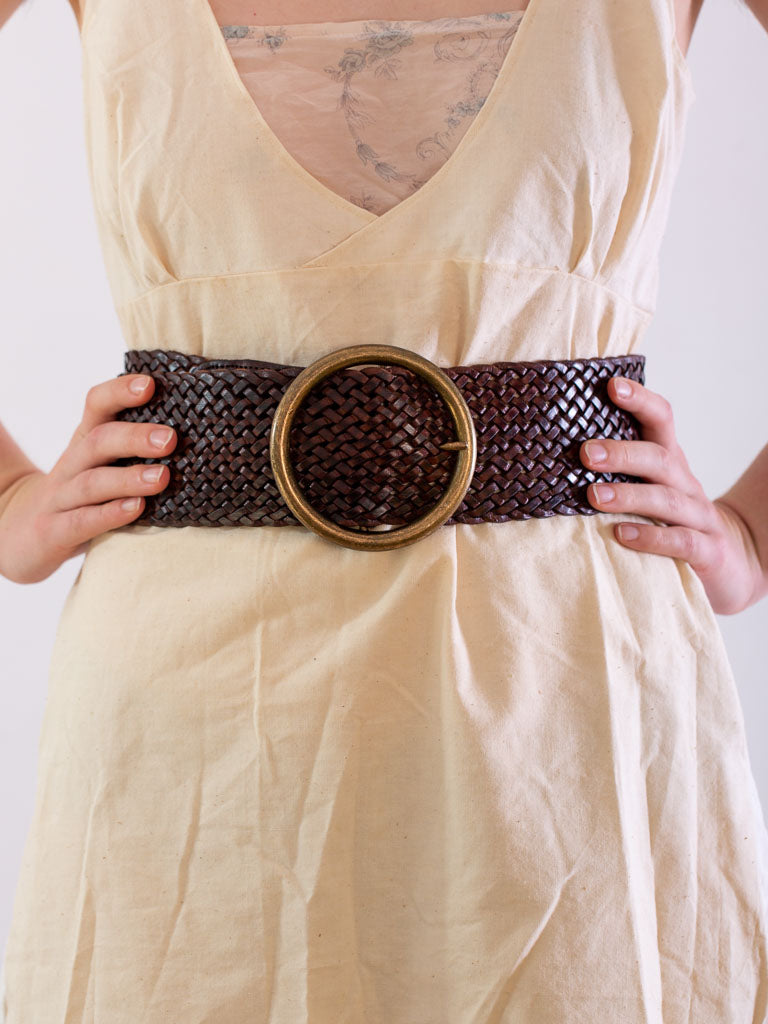 close of the waist wearing a wide chocolate leather woven belt., with a round brass buckle.