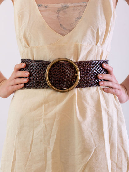 close of the waist wearing a wide chocolate leather woven belt., with a round brass buckle.